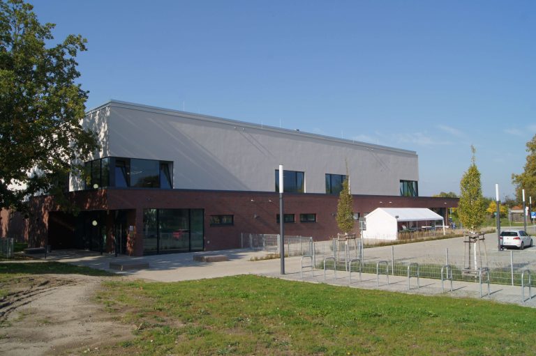 Zu sehen ist eine Dreifeldturnhalle in Wustermark in Brandenburg. Hier hat die Ritter Bauphysik GmbH die BAuakustik, die Raumakustik und den Immissionsschutz untersucht.
